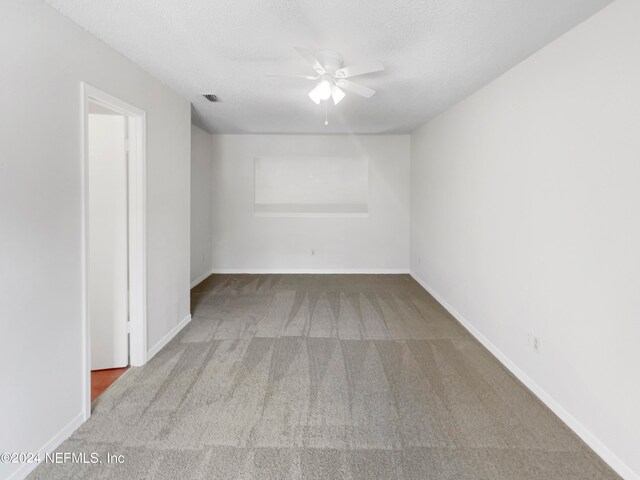 empty room with ceiling fan, carpet, and a textured ceiling