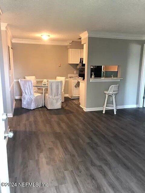 unfurnished living room featuring a textured ceiling, ornamental molding, and dark hardwood / wood-style flooring