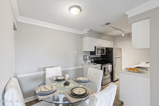dining room with a textured ceiling, crown molding, light wood finished floors, and visible vents