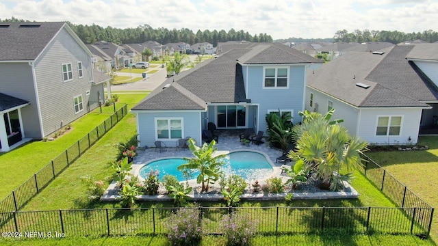 back of property featuring a lawn, a patio, and a fenced in pool