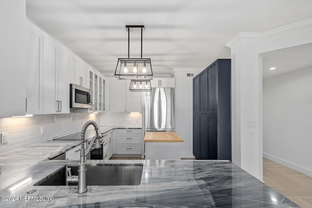 kitchen with ornamental molding, white cabinetry, decorative light fixtures, and sink