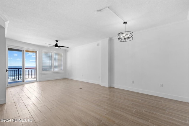 unfurnished room with a textured ceiling, ceiling fan with notable chandelier, light hardwood / wood-style floors, and crown molding