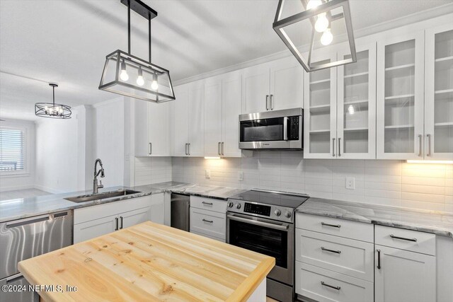 kitchen with sink, tasteful backsplash, decorative light fixtures, white cabinetry, and stainless steel appliances