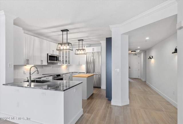 kitchen featuring white cabinetry, butcher block counters, sink, and decorative light fixtures