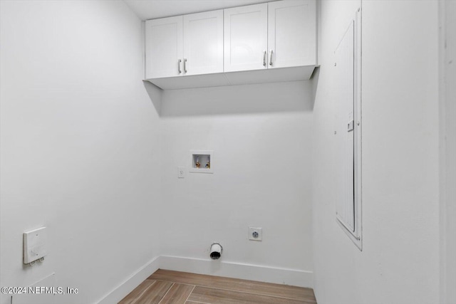 clothes washing area with cabinets, light wood-type flooring, hookup for an electric dryer, and washer hookup