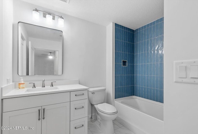 full bathroom featuring tiled shower / bath, vanity, toilet, and a textured ceiling