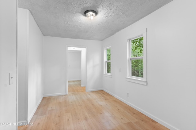 unfurnished room featuring a textured ceiling and light hardwood / wood-style flooring