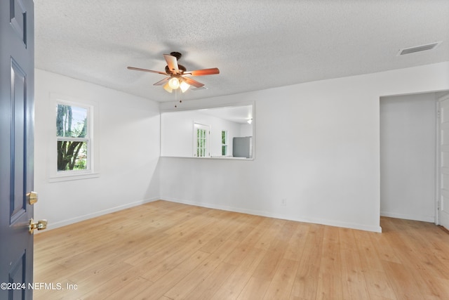 unfurnished room featuring light wood-type flooring, ceiling fan, and a textured ceiling