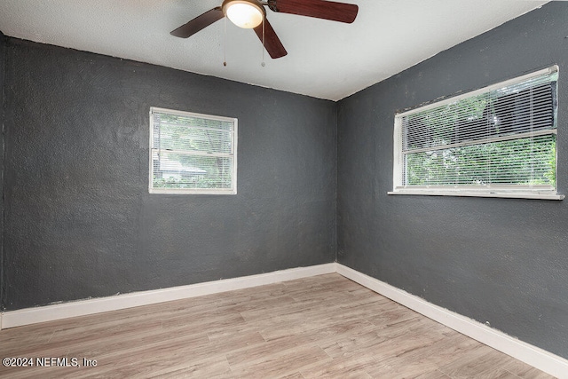 unfurnished room with a textured ceiling, a healthy amount of sunlight, ceiling fan, and light hardwood / wood-style floors