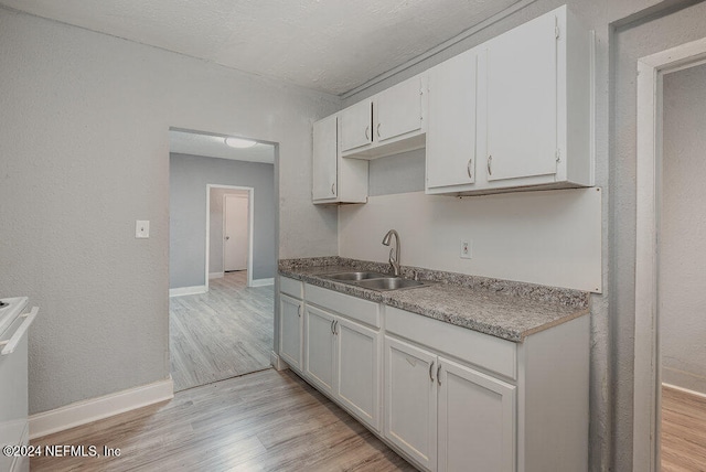 kitchen featuring light hardwood / wood-style flooring, white cabinets, a textured ceiling, and sink