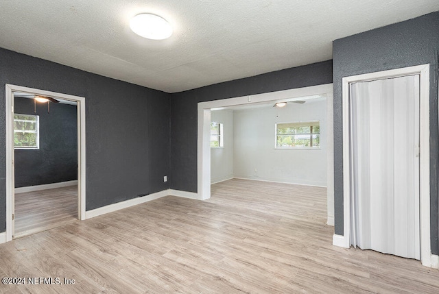 empty room with light wood-type flooring and a textured ceiling