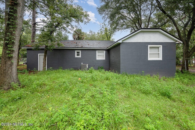 back of house with a lawn and central air condition unit