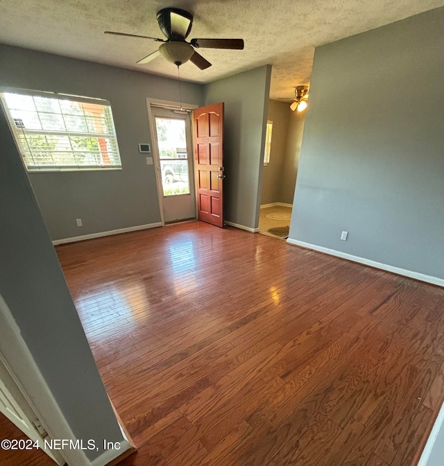 empty room with ceiling fan, a textured ceiling, and hardwood / wood-style floors