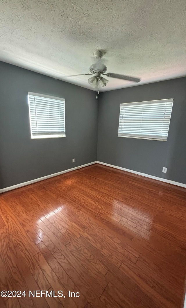 spare room featuring ceiling fan, a textured ceiling, wood-type flooring, and a wealth of natural light