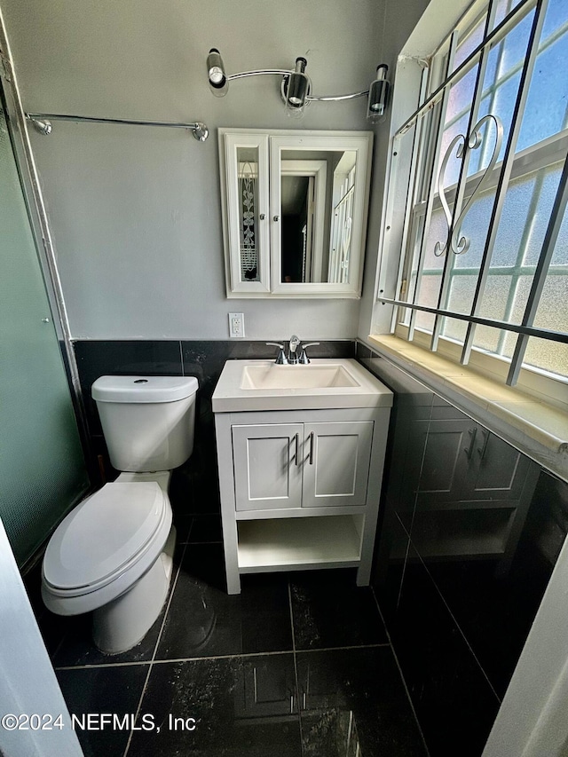 bathroom with a healthy amount of sunlight, tile walls, toilet, and tile patterned floors