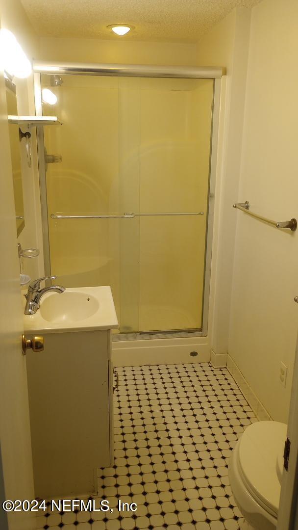 full bathroom with toilet, vanity, a stall shower, and a textured ceiling