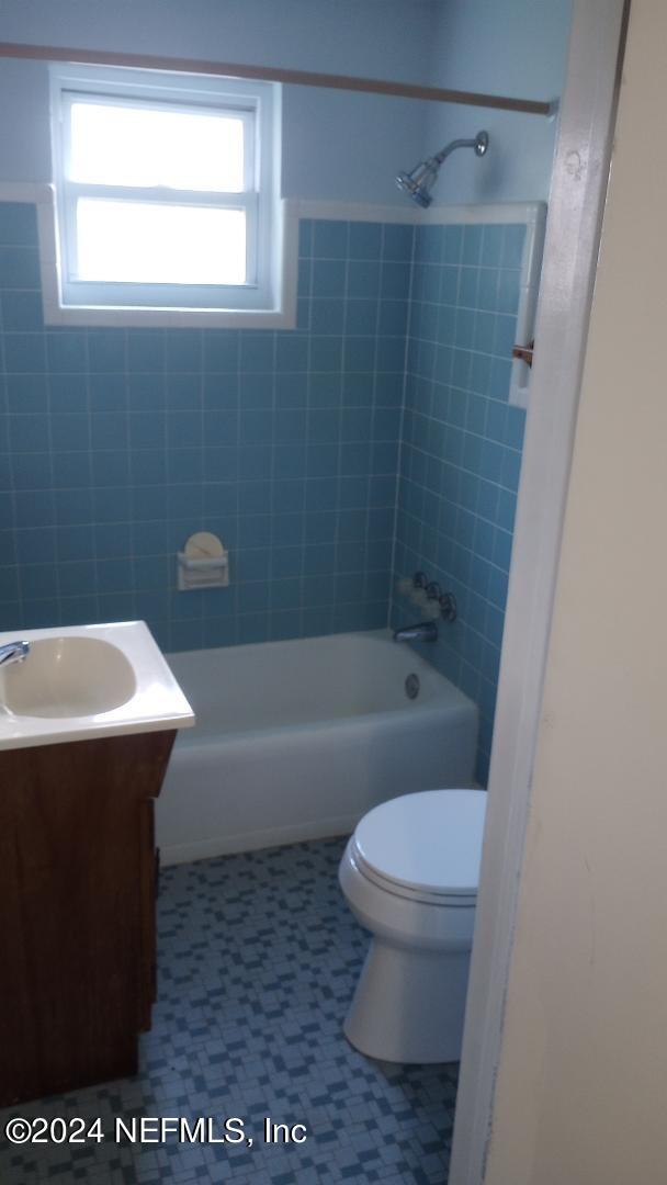 bathroom with toilet, vanity, and shower / washtub combination