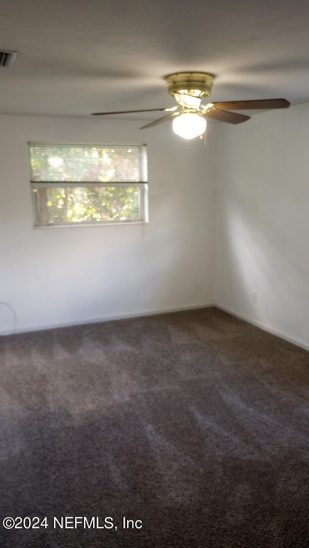 carpeted empty room with plenty of natural light, visible vents, and ceiling fan