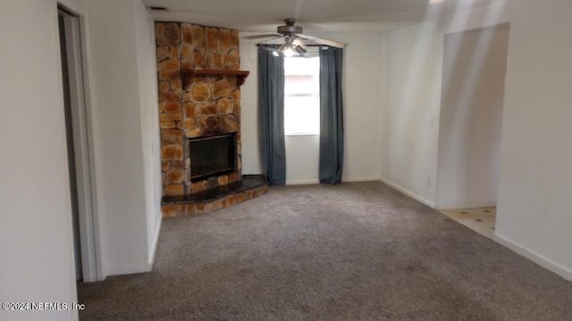 unfurnished living room featuring carpet floors, a stone fireplace, and ceiling fan
