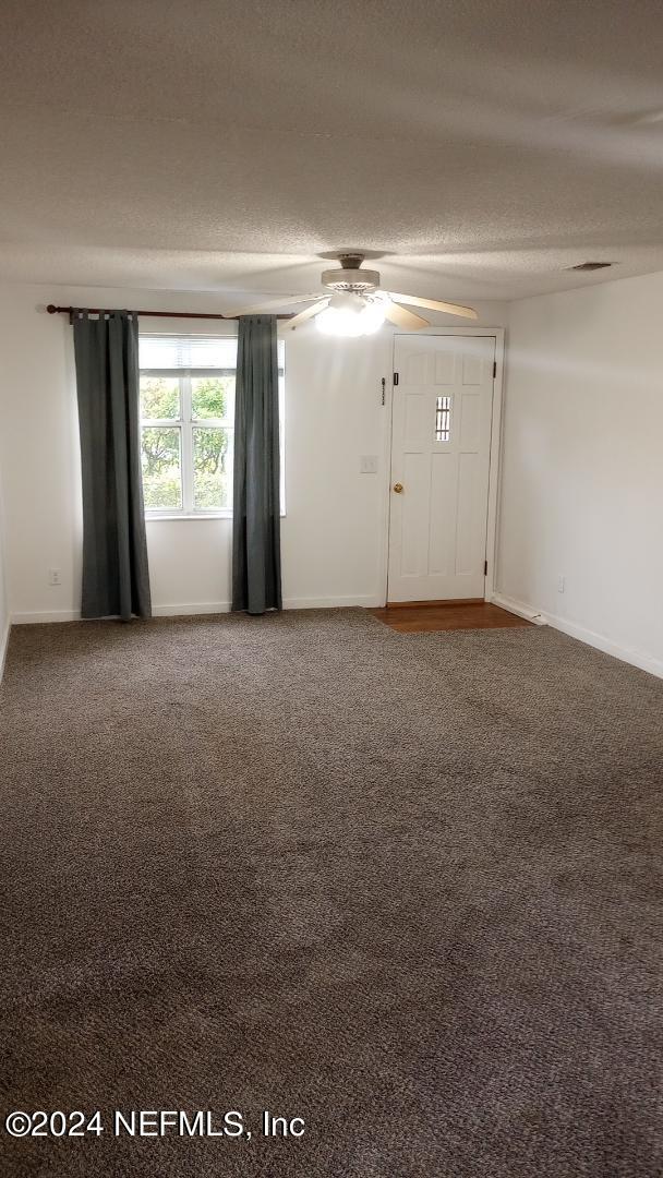 empty room with baseboards, ceiling fan, carpet, and a textured ceiling