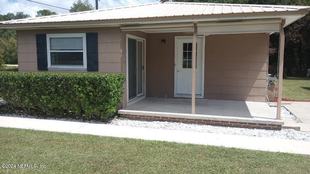 entrance to property featuring metal roof and concrete block siding