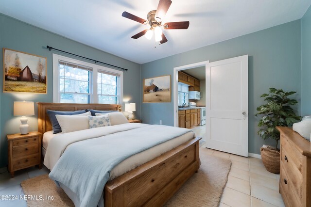 tiled bedroom featuring ceiling fan, sink, and connected bathroom