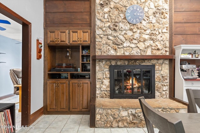 tiled living room with a stone fireplace