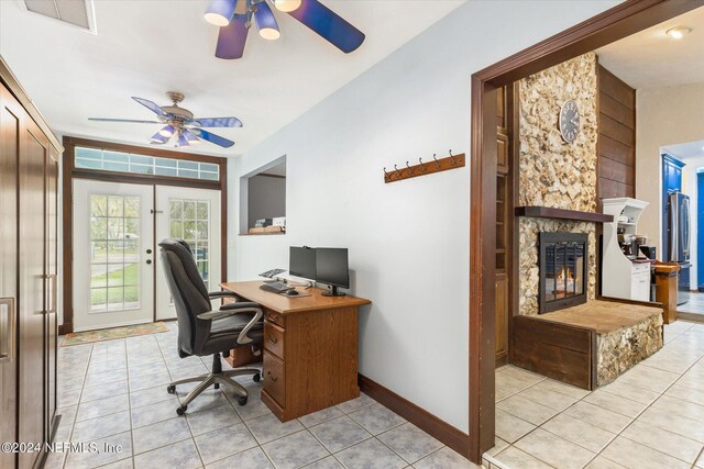 office area with french doors, ceiling fan, a fireplace, and light tile patterned floors