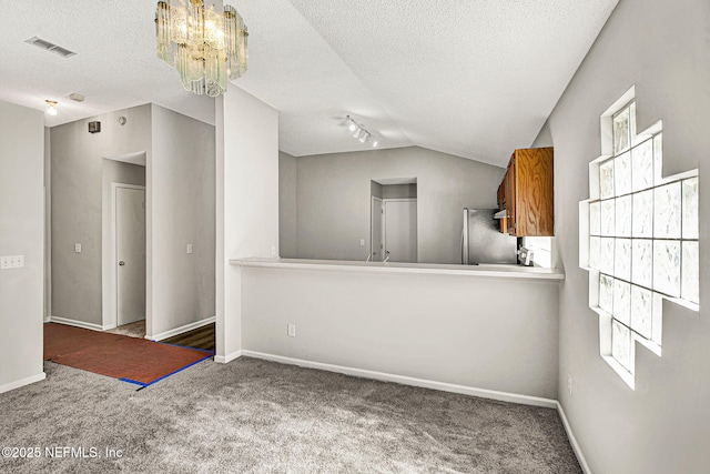 carpeted empty room featuring lofted ceiling, a wealth of natural light, and a textured ceiling