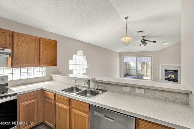 kitchen with pendant lighting, sink, stainless steel appliances, ventilation hood, and a textured ceiling