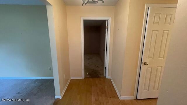 hall with baseboards and wood finished floors