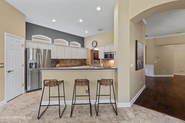 kitchen featuring decorative backsplash, light hardwood / wood-style floors, white cabinets, stainless steel appliances, and sink