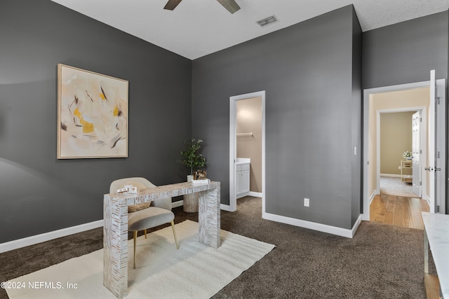 carpeted home office featuring a textured ceiling and ceiling fan