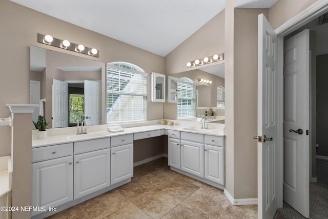 bathroom featuring a textured ceiling, vanity, vaulted ceiling, and tile patterned floors