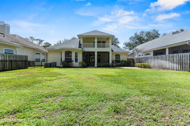 rear view of property with cooling unit, a balcony, and a yard