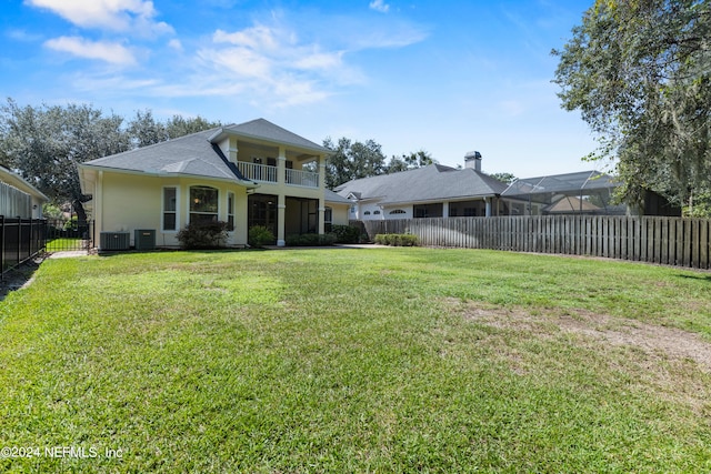 rear view of house featuring a balcony, central AC, a lanai, and a yard