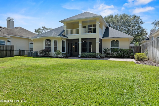 back of property with a balcony, cooling unit, and a yard