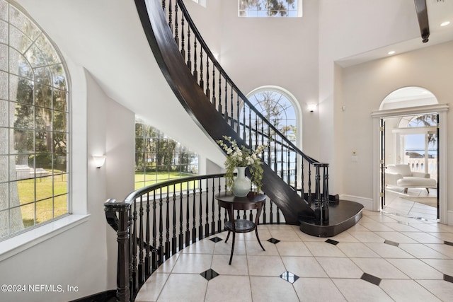 stairway with a towering ceiling and tile patterned flooring