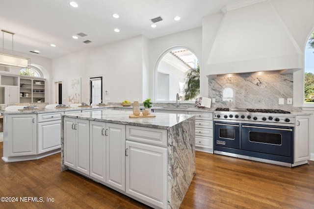 kitchen with double oven range, kitchen peninsula, a center island, and dark hardwood / wood-style floors