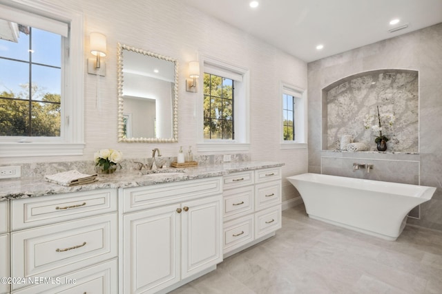 bathroom featuring a bathtub, tile walls, and vanity