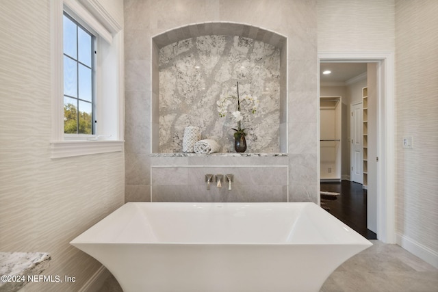 bathroom featuring ornamental molding, concrete floors, tile walls, and a bathtub