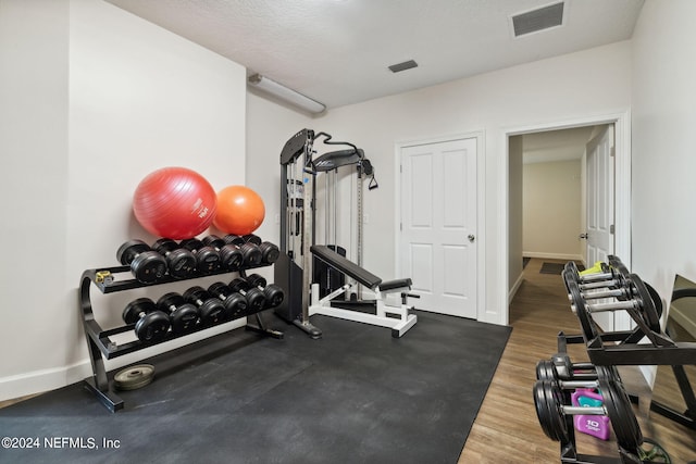 workout room with a textured ceiling and dark hardwood / wood-style floors