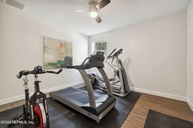 exercise area featuring ceiling fan, a textured ceiling, and dark wood-type flooring