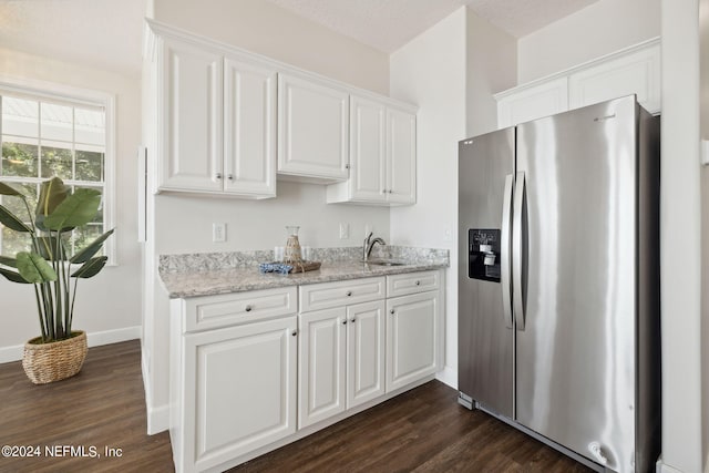 kitchen with light stone counters, stainless steel refrigerator with ice dispenser, dark hardwood / wood-style flooring, and white cabinetry