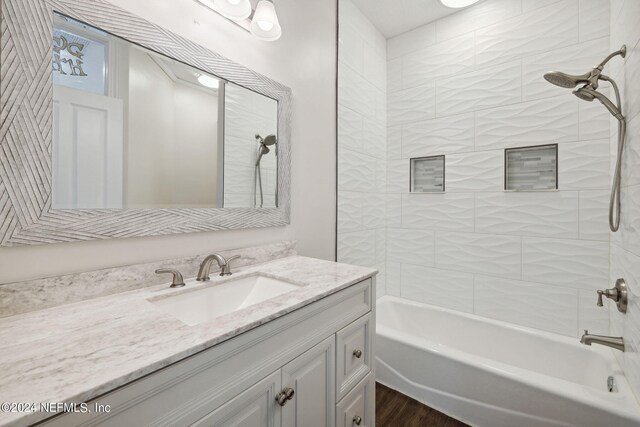 bathroom featuring tiled shower / bath combo, vanity, and wood-type flooring