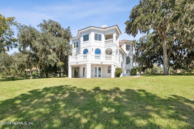 rear view of property with a balcony and a yard