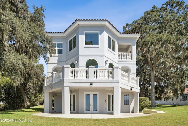 rear view of house with a lawn, a balcony, a patio area, and french doors