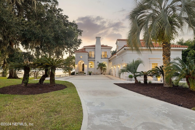 mediterranean / spanish-style house with a garage and a yard