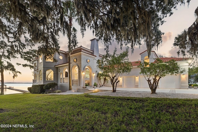 mediterranean / spanish-style home with a water view and a yard