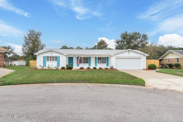 ranch-style home with an attached garage, fence, concrete driveway, and a front yard